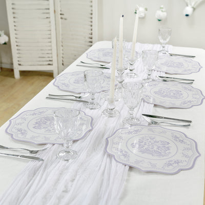 Elegant table setting with floral plates, glasses, and candles.