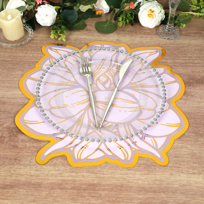 Decorative floral charger plate with silver cutlery on a rustic wooden table.