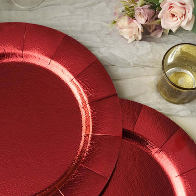 Red decorative plates on a textured table with flowers and a glass.