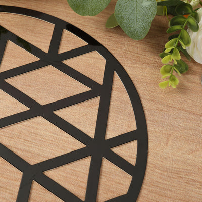 Black geometric decorative plate on a wooden surface with greenery.