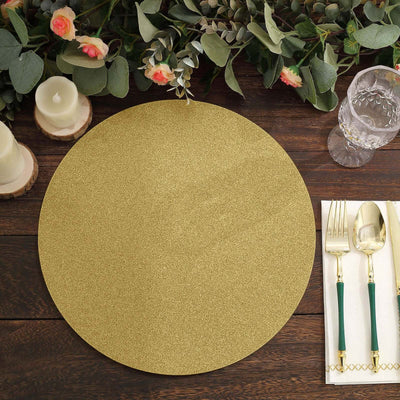 Gold glitter round placemat on a rustic wooden table with greenery and tableware.