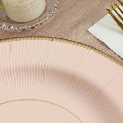 Pink decorative plate with gold accents on a wooden table setting.