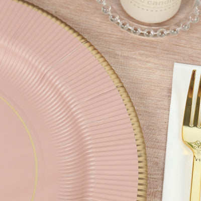 Pink decorative plate with gold rim on textured surface.