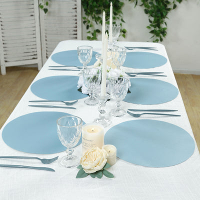 Elegant table setting with blue placemats, glassware, and floral accents.