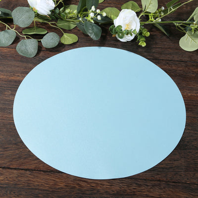Blue circular paper cutout on a wooden surface with greenery and flowers.