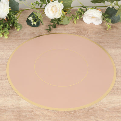 Round blush placemat with gold trim on a wooden table.