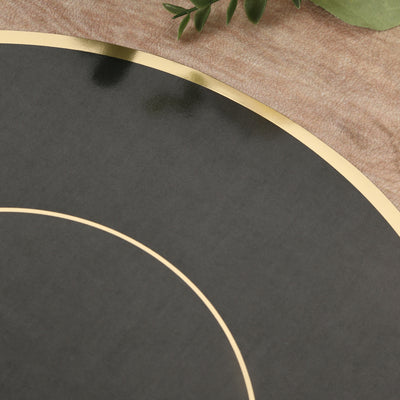 Black round placemat with gold trim on a textured surface.