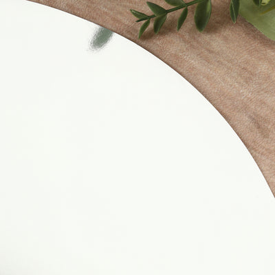 Reflective round mirror on wooden surface with greenery.