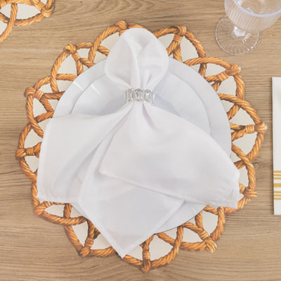 Elegant white napkin with a silver napkin ring on a decorative plate.
