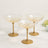 Set of three elegant gold-rimmed champagne coupes on a marble surface.