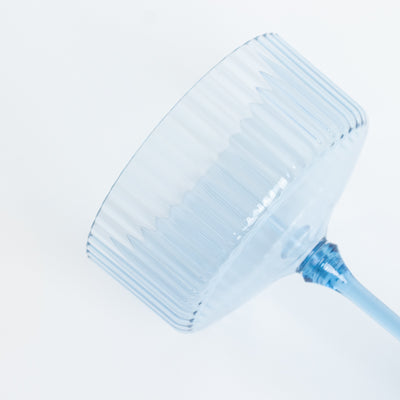 Blue ribbed glassware on a plain background.