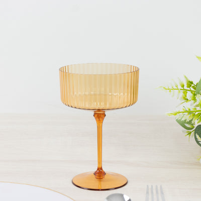 Amber ribbed cocktail glass on a plain background.