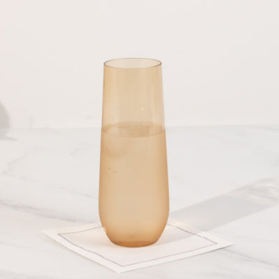 Amber glass tumbler with water on a white marble surface