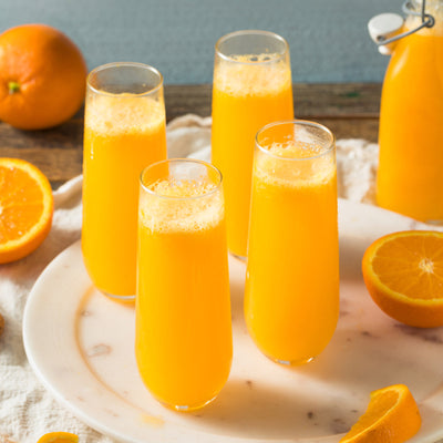 Fresh orange juice served in tall glasses with sliced oranges on a rustic table.
