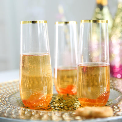 Elegant champagne flutes with gold rims on a decorative platter.