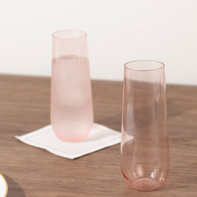 Two elegant pink glasses on a wooden surface.