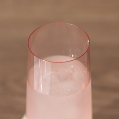 Pink drink in a tall glass with ice, viewed from above.