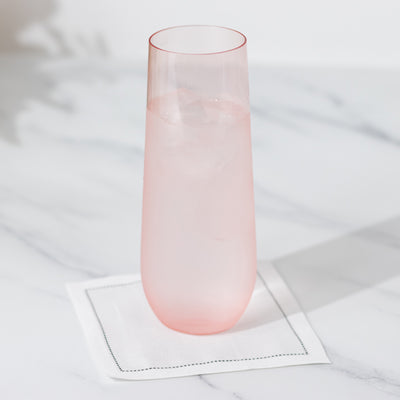 Pink glass with ice on a white napkin against a marble background.