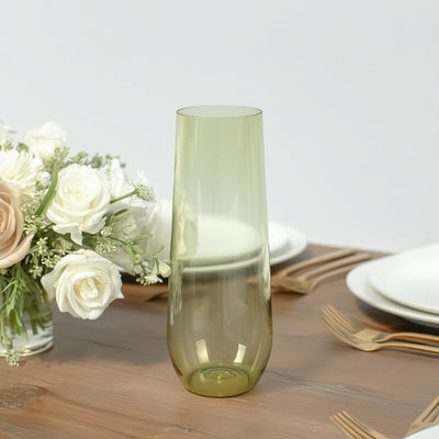 Green glass vase on a dining table with flowers and dinnerware.