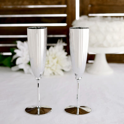 Elegant silver champagne flutes on a table with a floral backdrop.