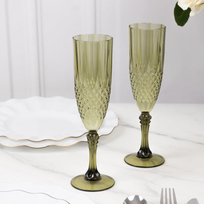 Elegant green crystal champagne flutes on a marble table.