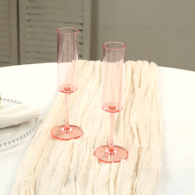 Pink champagne flutes on a textured table runner.