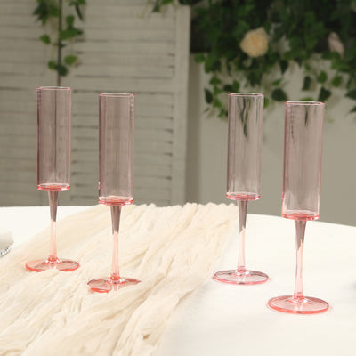 Elegant pink champagne flutes on a table with soft fabric backdrop.