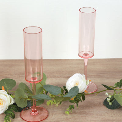 Pink champagne flutes on a wooden table with greenery accents.
