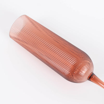 Rose gold ribbed cylindrical decorative vase on white background