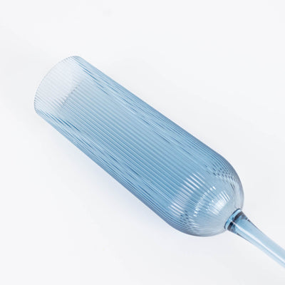 Blue ribbed glass bottle with tapered neck on white background