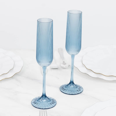 Blue ribbed champagne flutes on a white marble surface, elegant glassware set