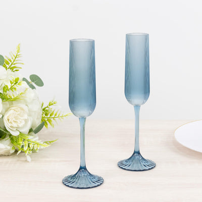 Blue ribbed champagne flutes on a white table with floral decor