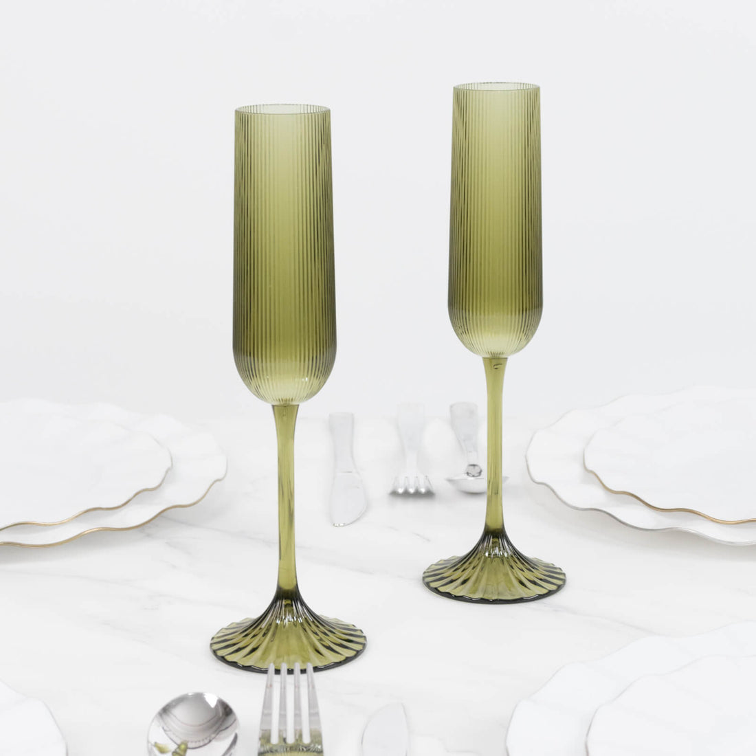 Olive green ribbed glass champagne flutes with fluted stems and pedestal bases