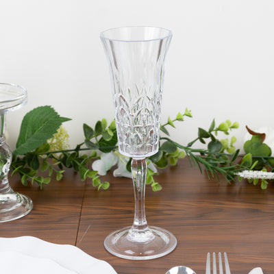 Elegant crystal champagne flute on a wooden table with greenery decoration.