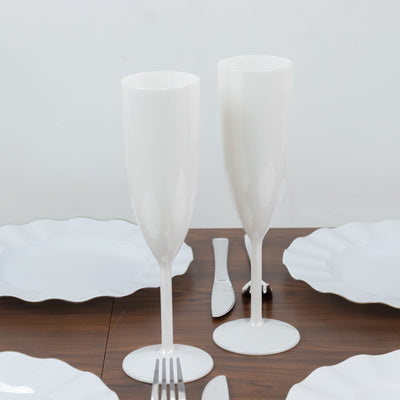White champagne flutes on a wooden table with white plates