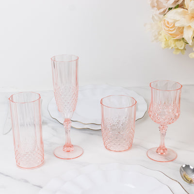 Elegant pink crystal glassware set on a marble table with white plates.