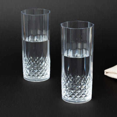 Two crystal clear tumblers filled with water on a dark background.