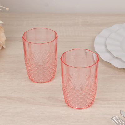 Set of two pink textured drinking glasses on a wooden surface.