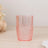 Pink crystal tumbler glass with a textured design on a wooden surface.