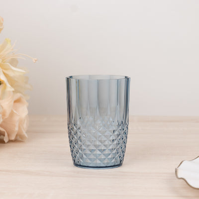 Blue textured glass tumbler on a wooden surface with flowers in the background.