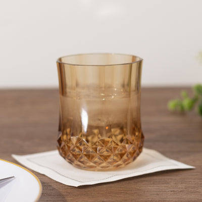 Amber glass tumbler on a wooden table with a coaster.