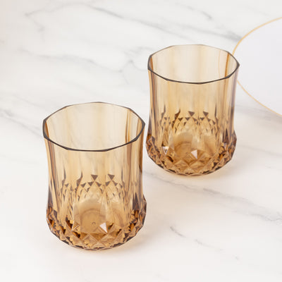 Amber glass tumblers with faceted design, perfect for stylish drinkware.