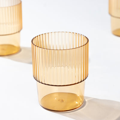 Amber ribbed drinking glass on a plain background