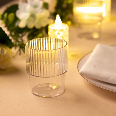 Clear ribbed plastic candle holder on a table with soft lighting.