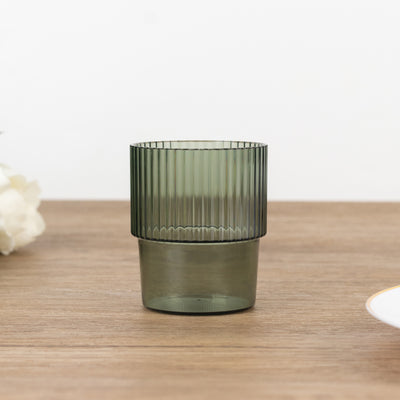 Green ribbed glass tumbler on wooden table.