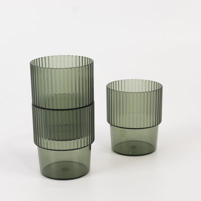Stacked green ribbed glasses on a white background