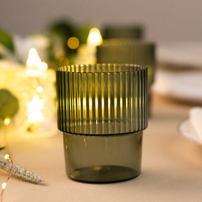 Green ribbed glass candle holder with soft ambient lighting.