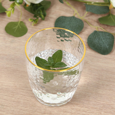 Glass tumbler with water and mint leaves, styled with gold rim.
