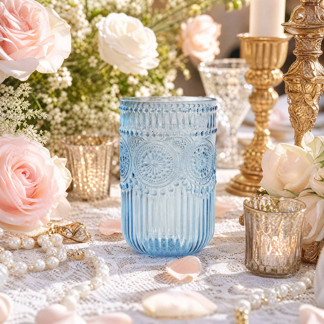 Blue decorative glass candle holder surrounded by pastel roses and gold accents