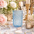 Blue decorative glass candle holder surrounded by pastel roses and gold accents